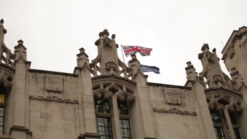 Union Jack flying above an ornate rooftop near Westminster Palace.