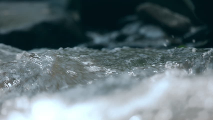 Palm hand touching on clear stream water in the rainforest waterfall. People travel and enjoy with nature. Slow motion shot.
