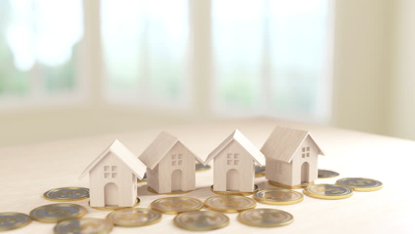 This image showcases multiple wooden house models placed on increasing stacks of coins, representing the concept of growth in real estate investment, highlighted by a natural light setting. Royalty-Free Stock Footage #3439123501