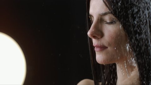 Beautiful woman head showering shampoo rinse in slow Motion. head of a  woman close up rinsing out shampoo under shower on black  background