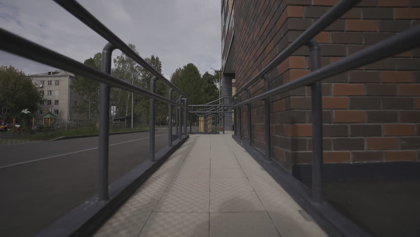 Long accessible terrace surrounds residential building on central street. Building with modern exterior design suitable for disabled people