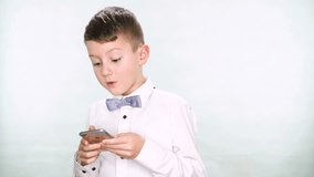 Baby boy shows thumbs up and playing with a tablet or smartphone on white background