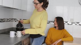 Caucasian lesbian couple in the kitchen getting ready to have a coffee to fast and start the day. LGBT couple concept