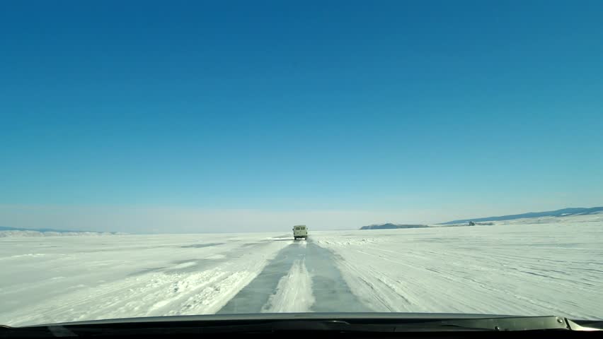 View of the UAZ car through the windshield. Driving on an icy roadway on frozen Lake Baikal. Popular tourist destination.