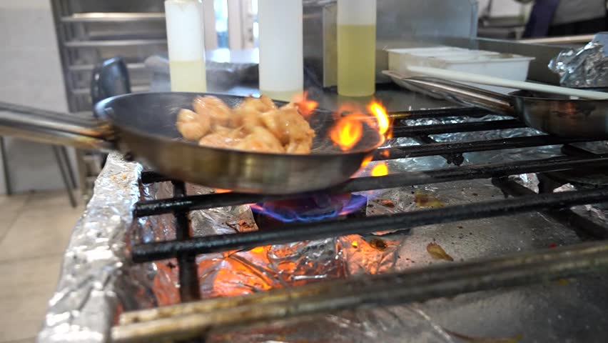 shrimp are fried in a frying pan on a gas grill