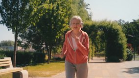 Senior female in a headset jogging in park, taking a break to catch her breath - Powered by Shutterstock - Get 15% off with code: PIKWIZARD15