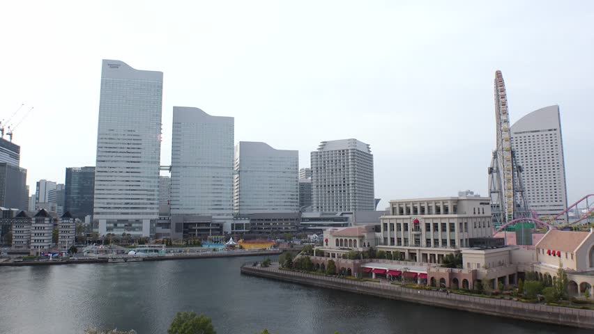 YOKOHAMA, JAPAN : Aerial view of cityscape of “Minatomirai“ area in sunset. Urban downtown area in central Yokohama city. View of buildings around the harbor. Tracking shot from ropeway (cable car).