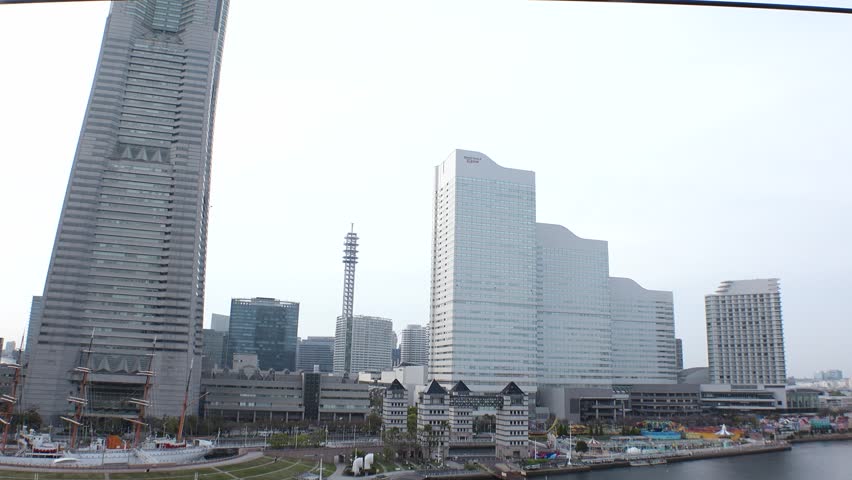 YOKOHAMA, JAPAN : Aerial view of cityscape of “Minatomirai“ area in sunset. Urban downtown area in central Yokohama city. View of buildings around the harbor. Tracking shot from ropeway (cable car).