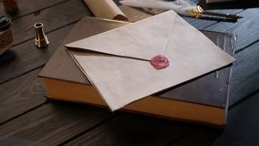 Shot of the desk with old paper envelope. Vintage love letter laying on the book sealed with wax stamp, feather quill and lighted candle around. - Powered by Shutterstock - Get 15% off with code: PIKWIZARD15