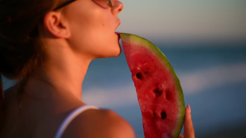 Young woman eating watermelon on beach. Happy summer time. Portrait of happy woman eat watermelon on beach.