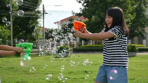 Cute Asian children Shooting Bubbles from Bubble Gun in the park  Stockvideó