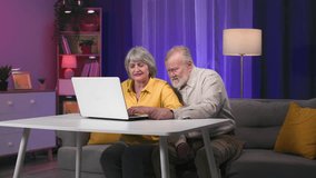 old elderly pensioners having fun playing games on a laptop while sitting at a table in room