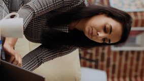 Vertical video Self employed woman sitting on couch, focused on finishing tasks in personal office. Freelancing businesswoman concentrating on inputting data on laptop, hurrying to complete project - Powered by Shutterstock - Get 15% off with code: PIKWIZARD15