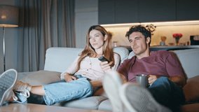 Married couple resting couch together. Smiling husband switching tv channels. Young family watching television selecting show at home interior. Two happy friends talking chilling on movie weekend - Powered by Shutterstock - Get 15% off with code: PIKWIZARD15