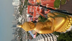 Vertical video. Aerial view of the Giant Golden Buddha in Bangkok with a beautiful city skyline in the background.