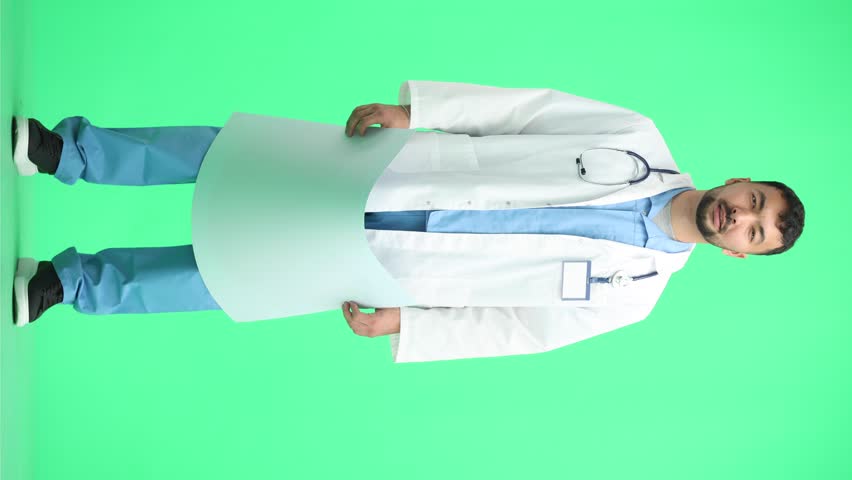 The doctor, in full height, on a green background, shows a white sheet