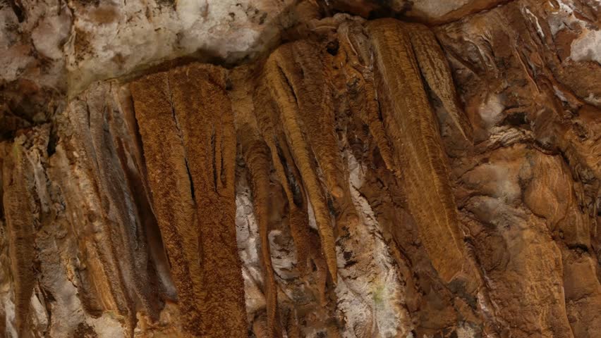 Close-up of brown stalactites in a cave, displaying intricate natural patterns and geological beauty.