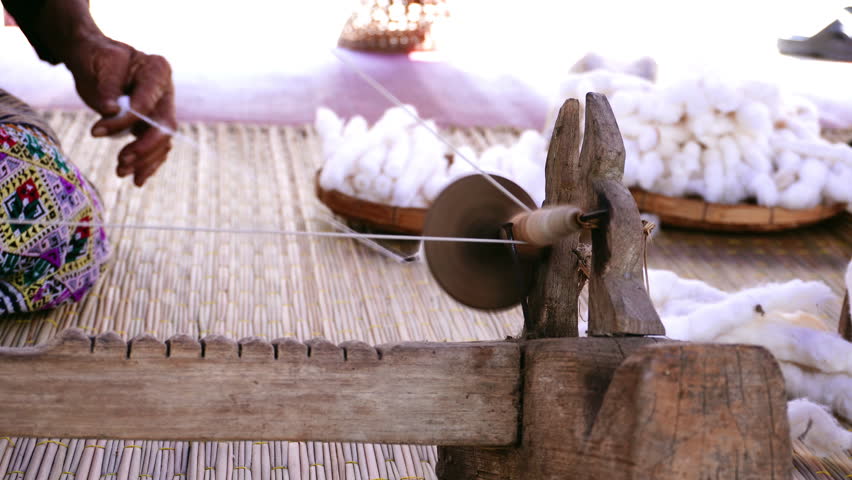 Close-up of a woman spinning thread in a spinning machine which is a tool used to spin cotton into tight threads threads. Thailand traditional.