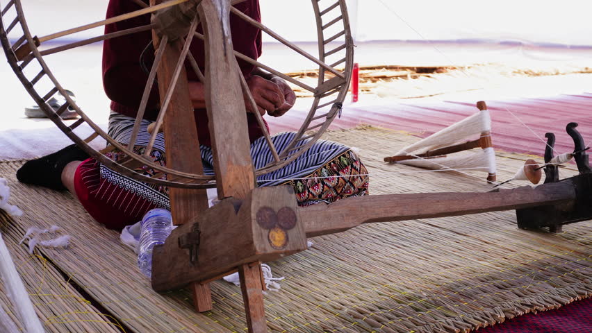 Close-up of a woman spinning thread in a spinning machine which is a tool used to spin cotton into tight threads threads. Thailand traditional.