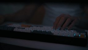 Detail cropped shot of unrecognizable gamer male pressing keys on wireless RGB mechanical keyboard with colorful keycaps with ASMR sounds, sitting at desk in dark room. Shooting in slow motion - Powered by Shutterstock - Get 15% off with code: PIKWIZARD15