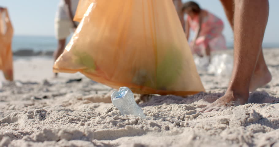 Diverse volunteers collect trash on a sandy beach, with copy space. The cleanup activity highlights environmental awareness and community involvement, slow motion. Royalty-Free Stock Footage #3439760437