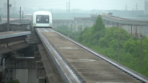 Shanghai maglev arrives at station with raised subway behind. Taking people to Pudong airport, China's fastest train, a magnetic levitation train that takes passengers to the local airport.