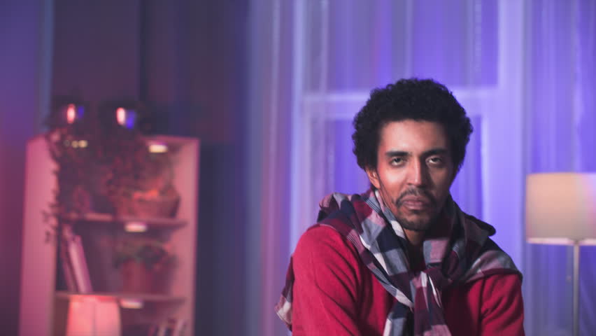 young black man having fun dancing and singing in cozy room, looking at camera