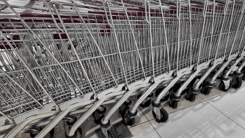 Row of empty shopping carts lined up at a supermarket, concept of retail industry and consumerism, suitable for sales promotions or Black Friday shopping themes Royalty-Free Stock Footage #3439820813