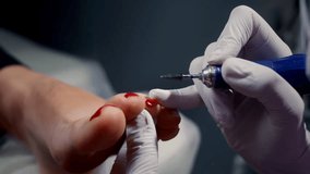 Manicurist cleans customer toenail from red acryl gel with electric polisher in pedicure salon closeup. Cosmetologist removes colour polish from nail with drill in shop. Master and lady client - Powered by Shutterstock - Get 15% off with code: PIKWIZARD15