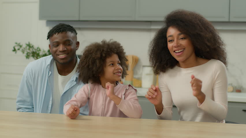 Carefree African American family biracial ethnic happy parents and cute little child girl kid dancing to music having fun together in kitchen at home funny mother father with daughter enjoying dance Royalty-Free Stock Footage #3439944513