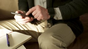 Man writing notes while using phone at home. Young businessman searching information on the internet with smartphone. Man working from home