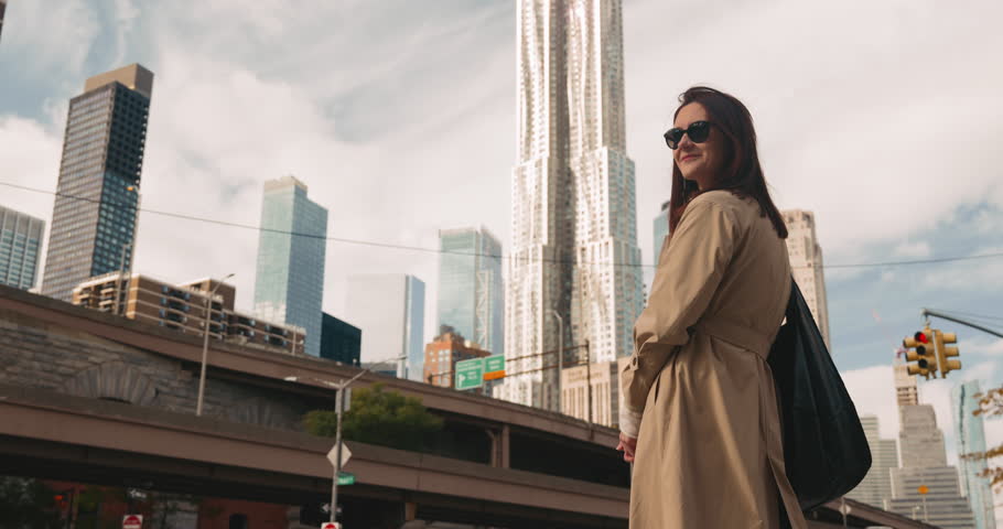 Stunning happy woman in sunglasses looking around and smiling against the backdrop of the New York cityscape