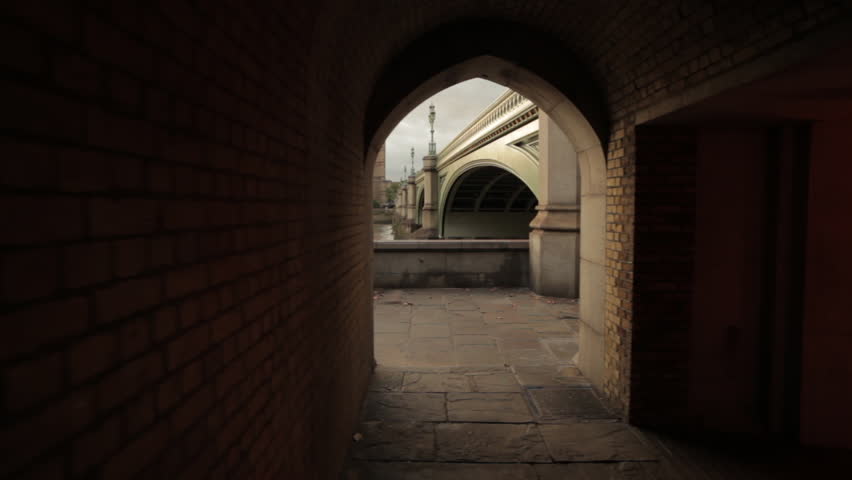 A shot of an archway in a tunnel underneath the bridge that shows Big Ben in