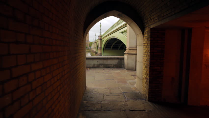 A shot of an archway in a tunnel underneath the bridge that shows Big Ben in