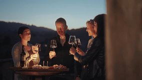 Group of friends enjoying wine tasting with local cheese, prosciutto and wine at sunset. Countryside vineyards and mountains in the background. Happy adult friends having fun, drinking wine and eating - Powered by Shutterstock - Get 15% off with code: PIKWIZARD15