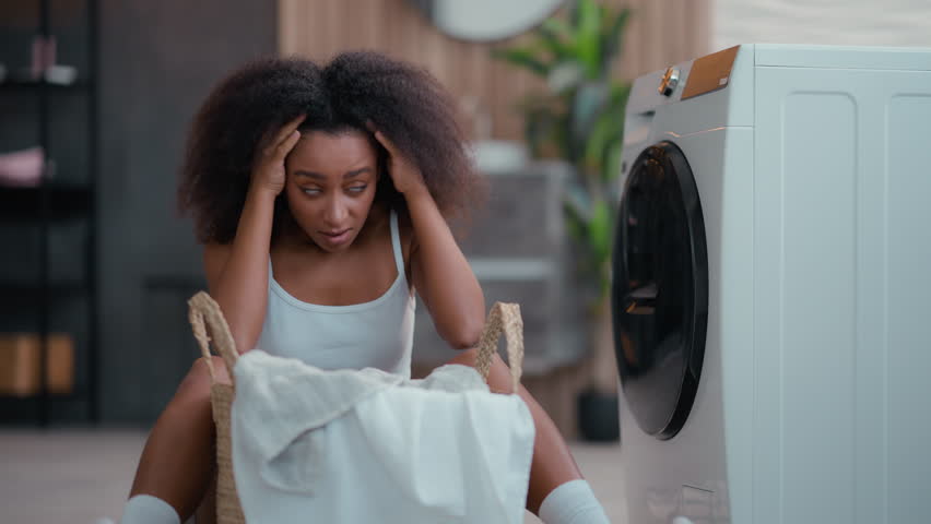 Angry sad woman upset irritated tired annoyed frustrated African American girl ethnic female biracial housewife exhausted with homework dirty cloth anger with laundry at home washing machine household