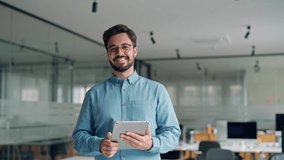 Smiling busy young latin business man manager using tablet computer, happy hispanic businessman executive looking at camera holding tab working standing in office. Portrait. - Powered by Shutterstock - Get 15% off with code: PIKWIZARD15