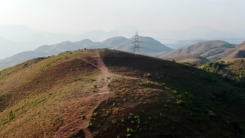 Mountain aerial flight above people hiking along trail path in sunny day. Group of friends summer adventure journey in nature outdoors
