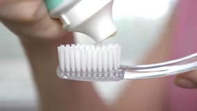 Squeezing toothpaste from a tube onto a toothbrush. Macro, close-up 4k. slow motion, copy space - Powered by Shutterstock - Get 15% off with code: PIKWIZARD15