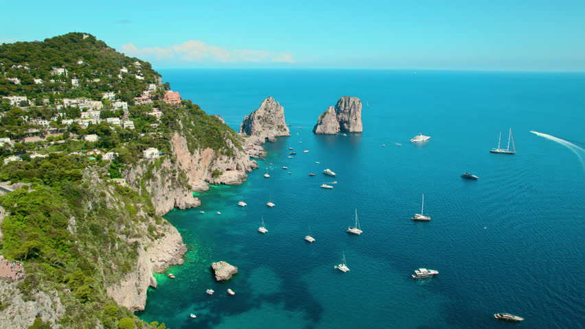 Yachts and boats dot the turquoise sea waters of Capri coast in Italy. Water activities during summer vacations. Aerial view of seascape. Royalty-Free Stock Footage #3440131869