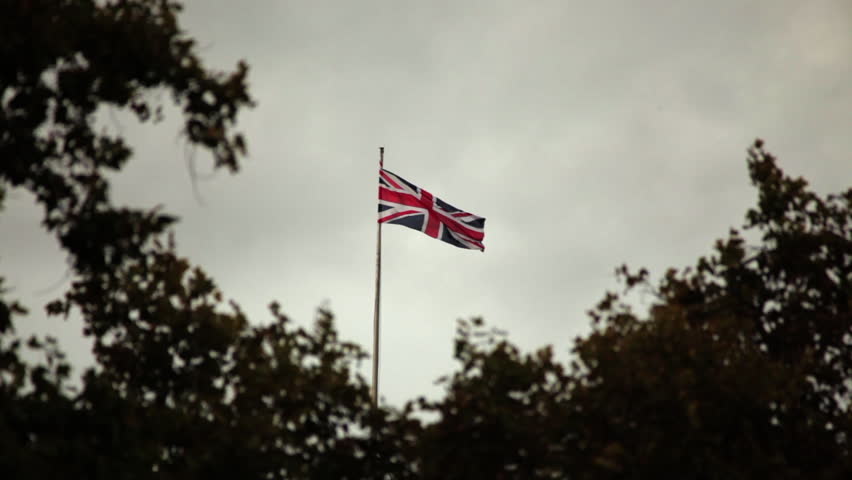 Union Jack waving in London, trees in the foreground. 