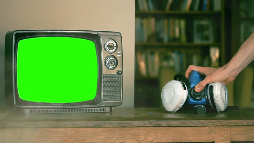 A Man Picking Up A Respirator Mask Near An Old TV Green Screen. Close Up. 4K Resolution.