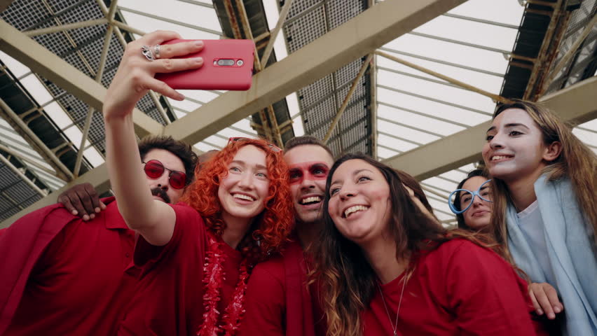 Cheerful male and female fans recording a video with their phone while watching the game at the stadium. High quality 4k footage