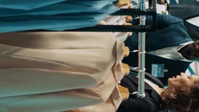 Vertical Video Employees team presenting variety of clothes to senior client, helping her to choose the perfect shirt size to create a formal outfit. Diverse store assistants show clothing from