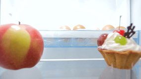 4k video of young woman taking fresh apple from fridge at kitchen. Concept of healthy food and nutrition