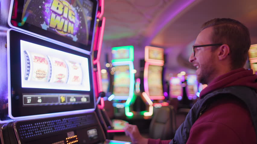 A delighted male gamer celebrating a win at a slot machine in a casino environment, celebrating his luck in hotel, Big Win, Las Vegas, USA. Slow Motion, Camera 4K RAW.  Royalty-Free Stock Footage #3440426285