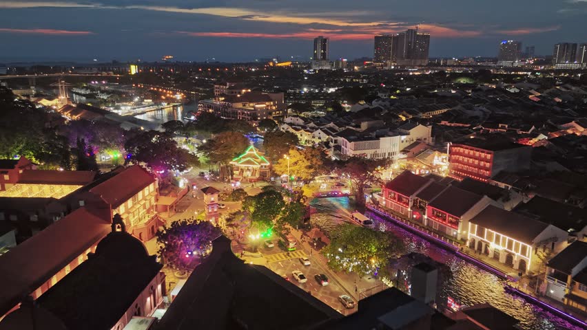 Aerial evening shot of Malacca city center, Melaka Tengah District, Malaysia. River with embankment, ancient colonial buildings with illumination in Malacca. Red sunset sky at background Royalty-Free Stock Footage #3440452121