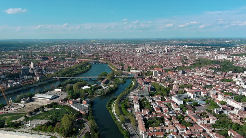 Toulouse aerial panoramic view. It's the capital of Haute Garonne department and Occitanie region in France. Terra-cotta bricks used in many of its buildings ft Garonne River and urban city skyline 4K