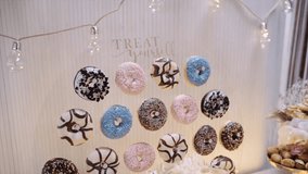 Handheld shot of various donuts hanging on circular glass at buffet table in restaurant - Powered by Shutterstock - Get 15% off with code: PIKWIZARD15