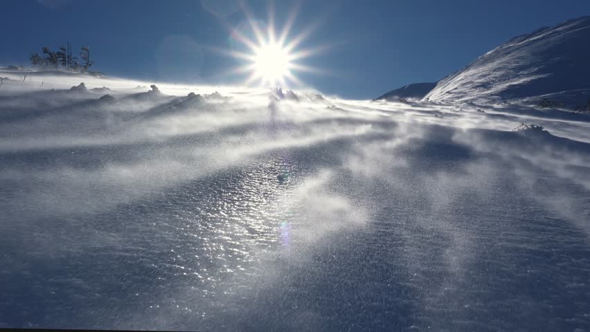 Windy day in winter alpine mountains, wind blowing snow in frozen nature